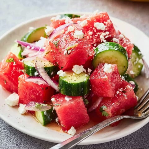 A plate of watermelon salad with feta cheese and onions.