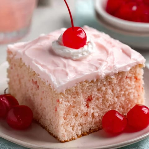 A slice of pink cake with a cherry on top.