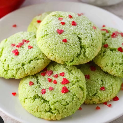 A plate of green cookies with red hearts on top.