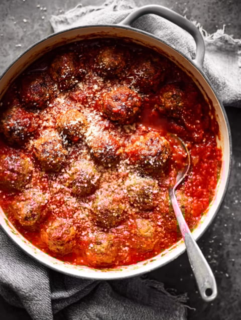 A bowl of meatballs covered in tomato sauce.