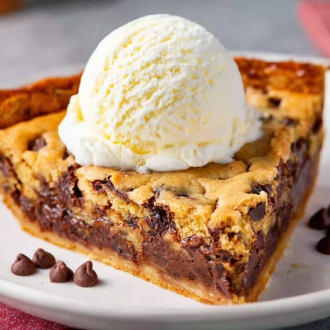 A slice of Tollhouse cookie pie with a scoop of ice cream on top.