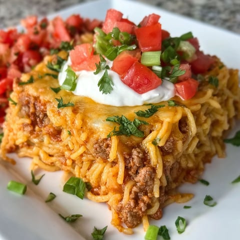 A plate of food with a cheesy taco spaghetti casserole.