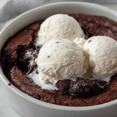 A bowl of chocolate cake with ice cream on top.