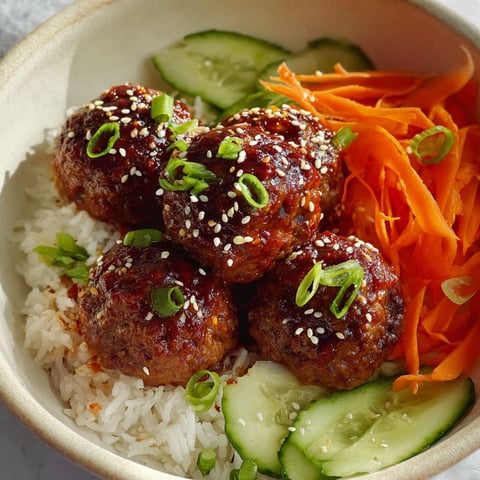A bowl of meatballs with rice and vegetables.