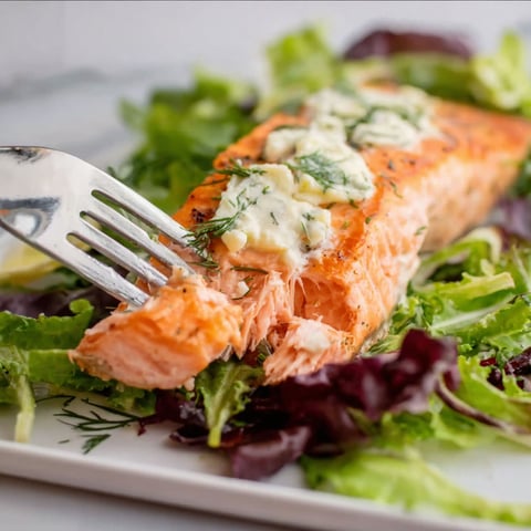A fork is stuck in a piece of salmon.