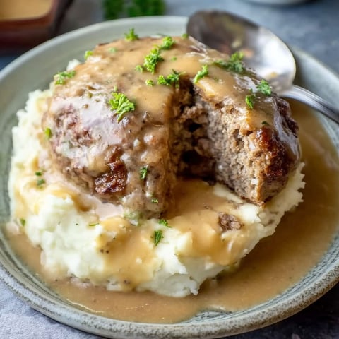Hamburger steak with gravy on a plate.